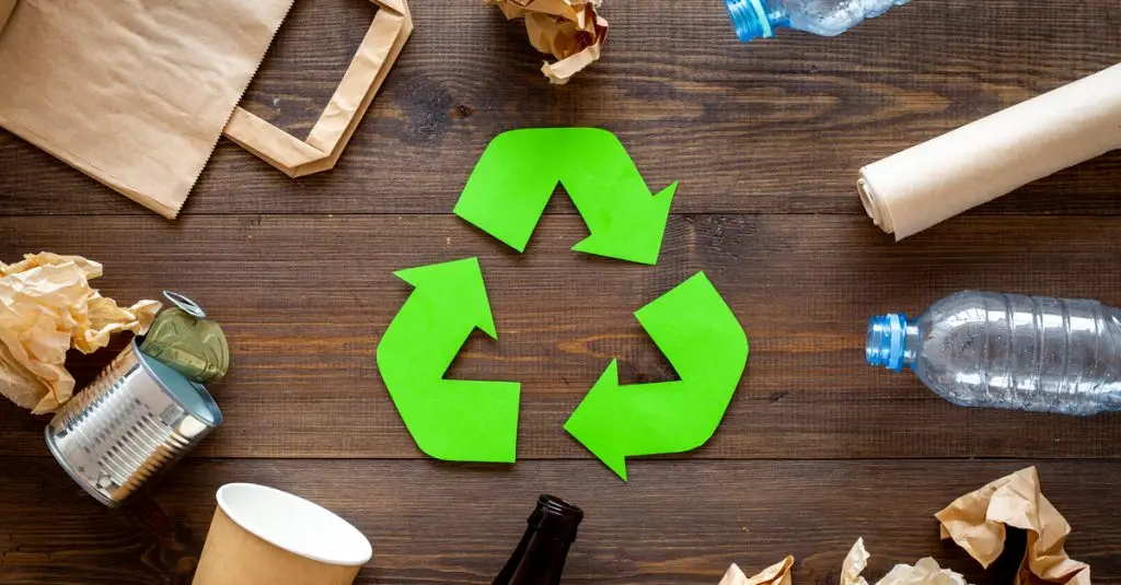 Mesa com resíduos recicláveis com a logo da reciclagem