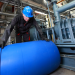 Trabalhador movendo barril de produtos químicos na indústria