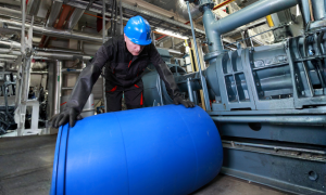 Trabalhador movendo barril de produtos químicos na indústria