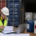 Trabalhador no porto, conferindo documentos para a exportação de produtos químicos